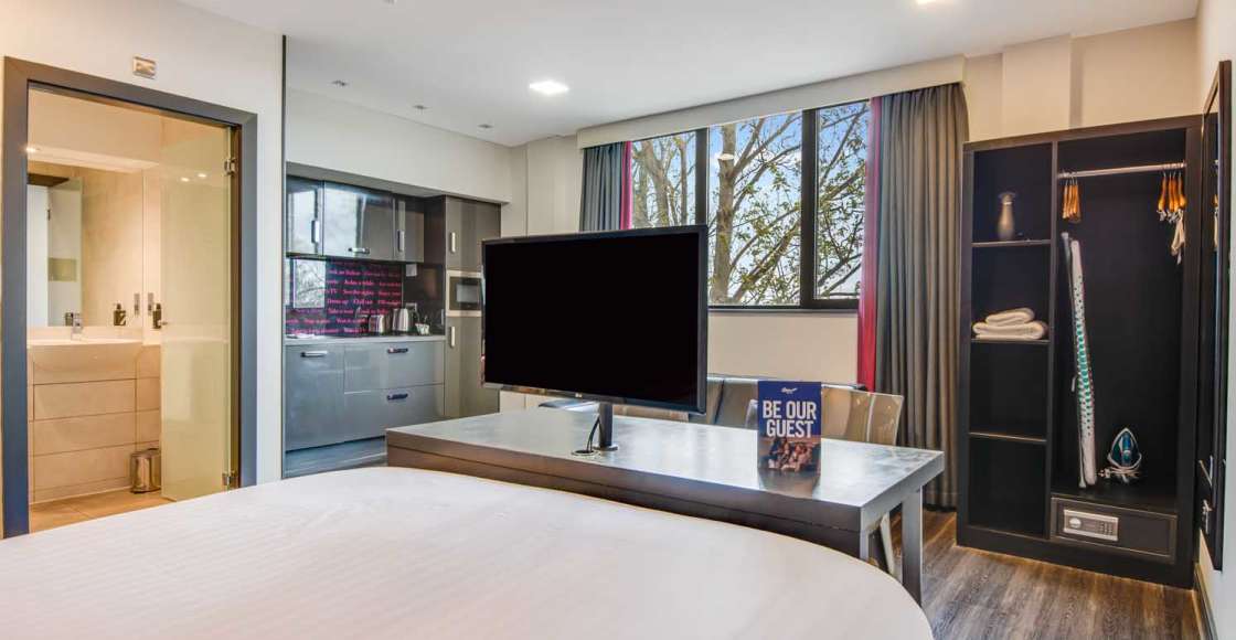 Smart Studio apartment view from king size bed with desk, kitchen, wardrobe, safe and television.