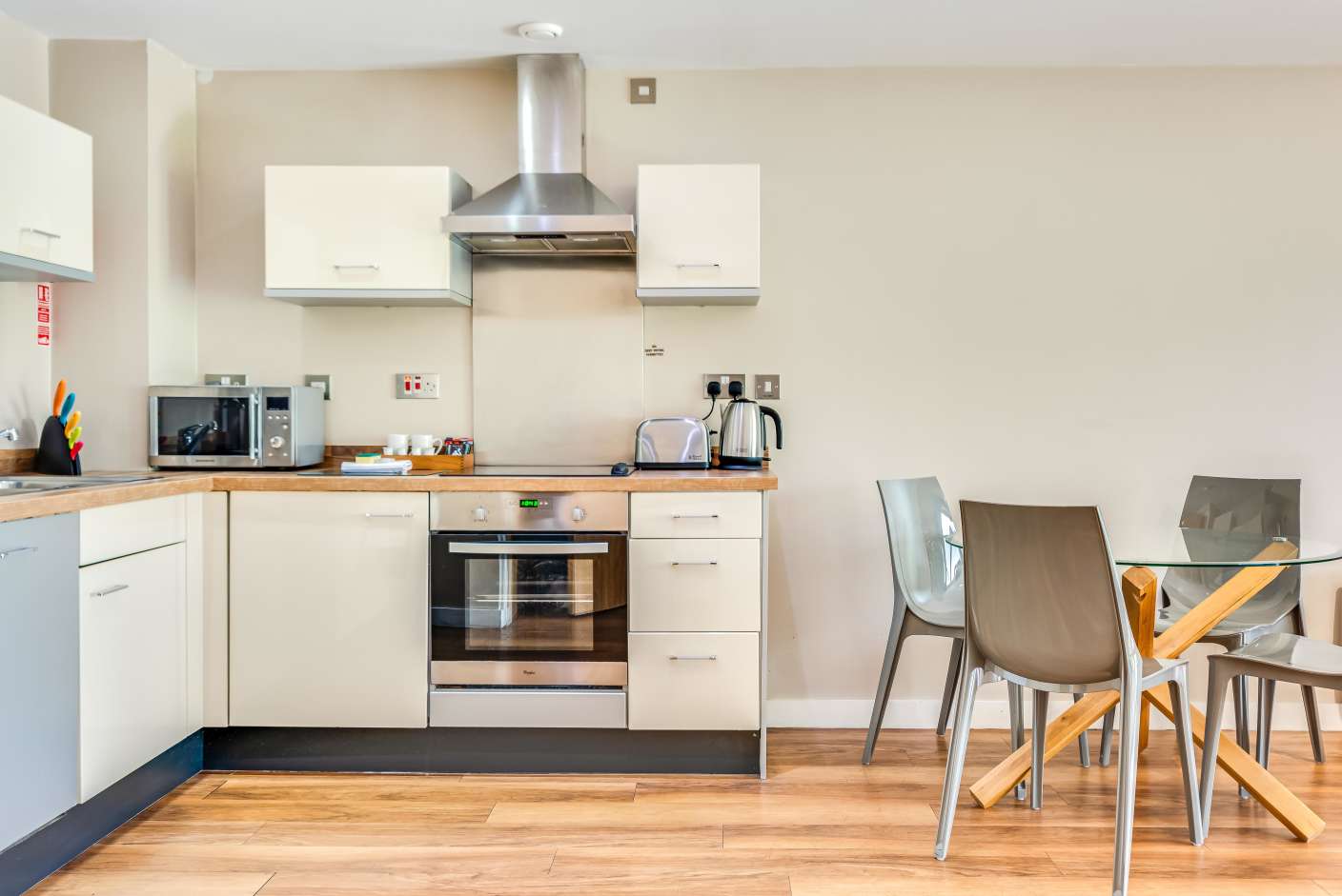 Kitchen with full oven, microwave, cream units, dishwasher and dining table. 