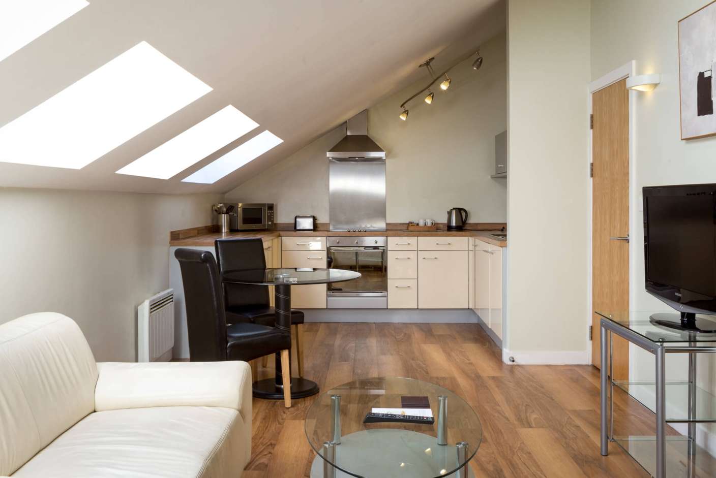 Living and Kitchen area with Dining Table, full oven and TV.